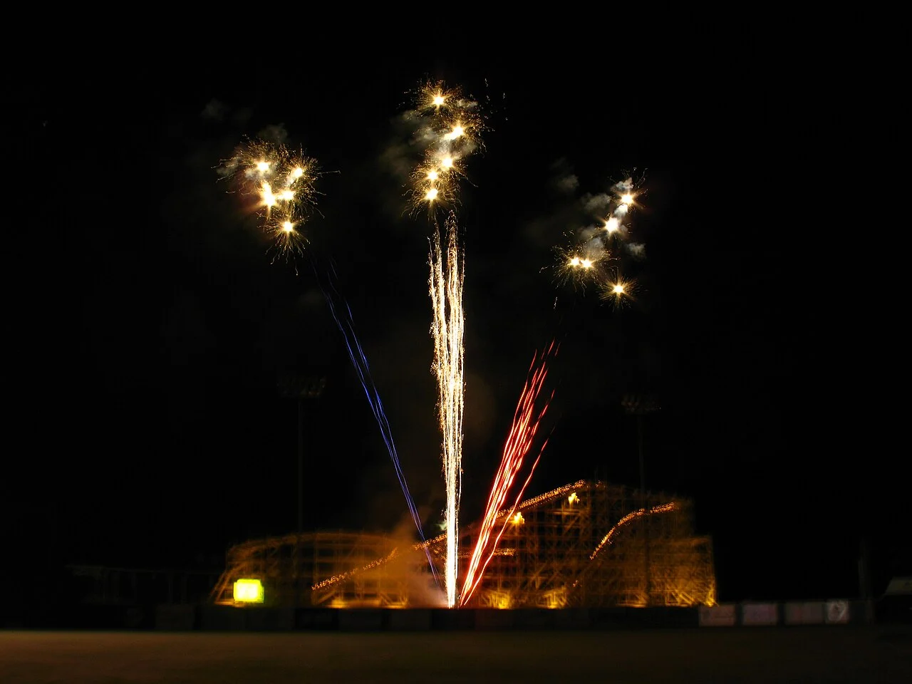 Open park with clear line of sight to fireworks over city skyline.