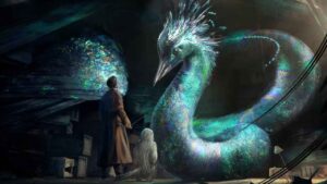 A detailed illustration for a fantasy film. At the top, the title "FANTASTIC ANIMALS" reads "UNCOVER THE MAGIC." Below, a young man in a brown jacket holds a magical staff and book. Around him are a colorful griffin, a red dragon, a blue niffler on coins, and deer in a castle landscape with two moons. The bottom edge contains credit text for the fantastic animals movie.